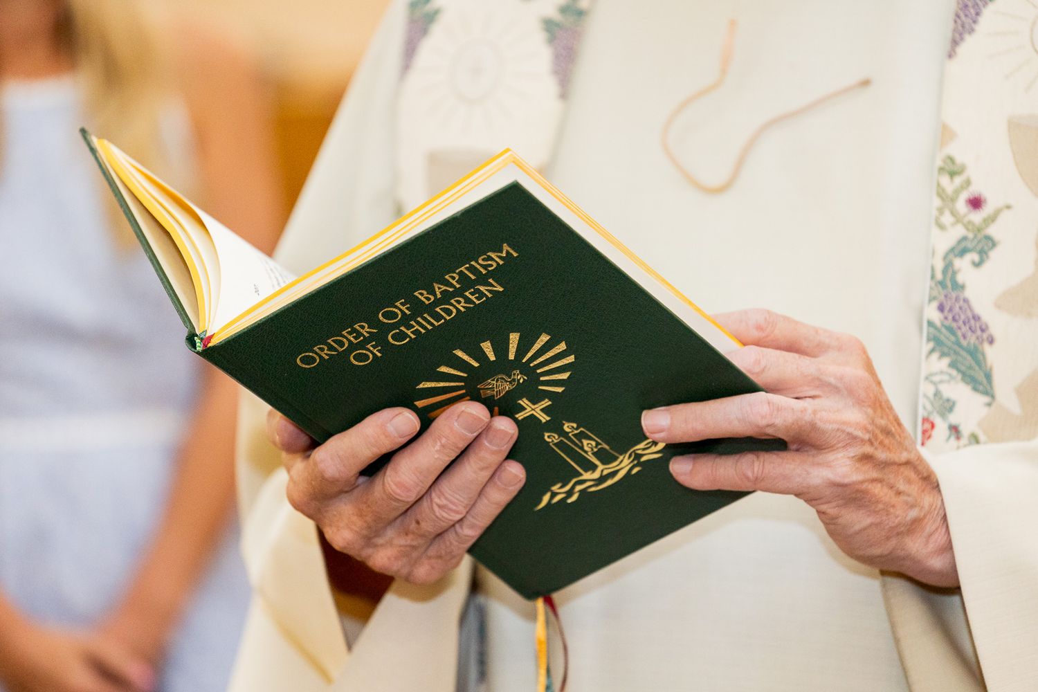 A green religious book is held open in hands during a spiritual ceremony.