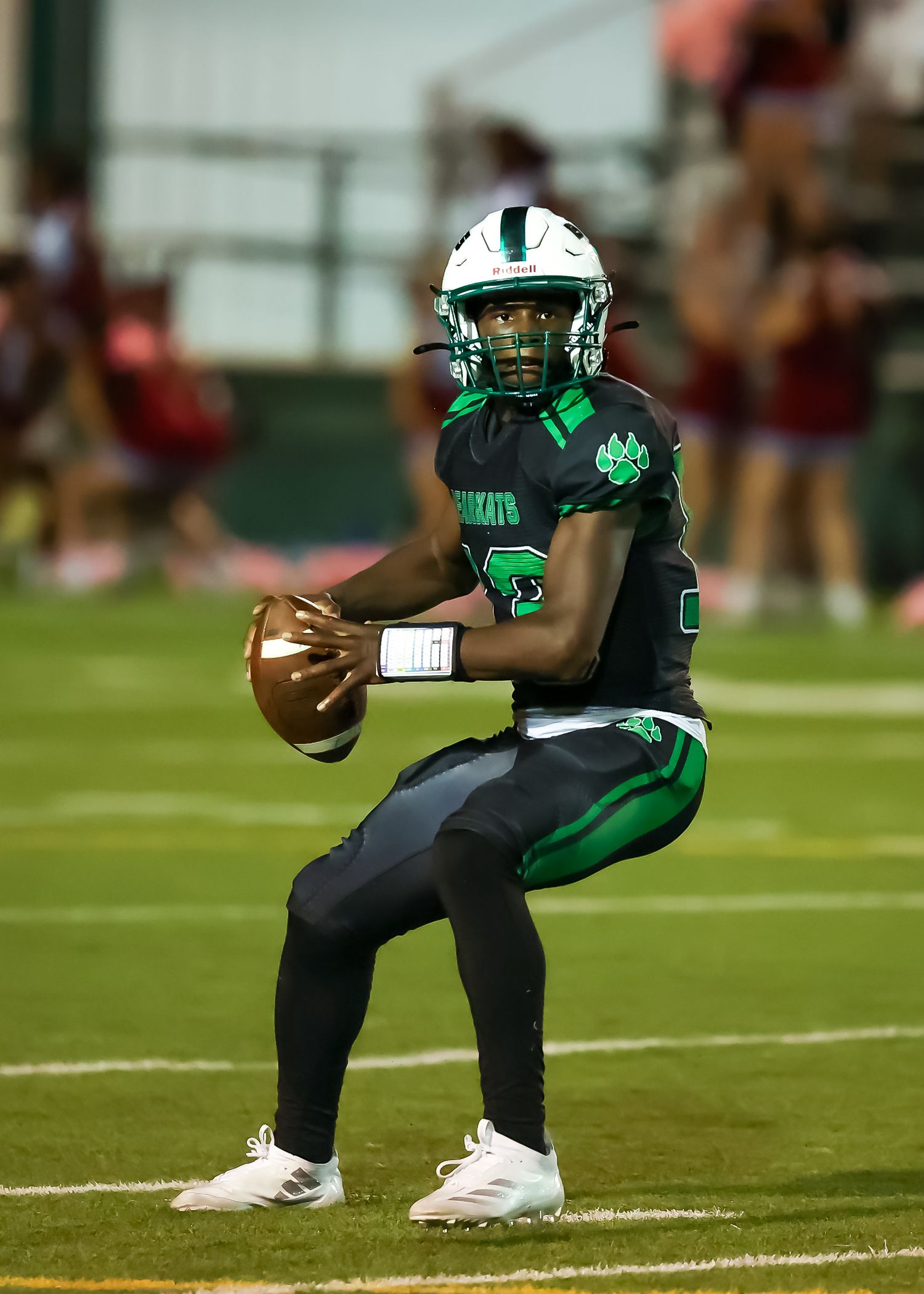 Football player in green and white uniform performs sideline throw sequence showing follow-through motion.