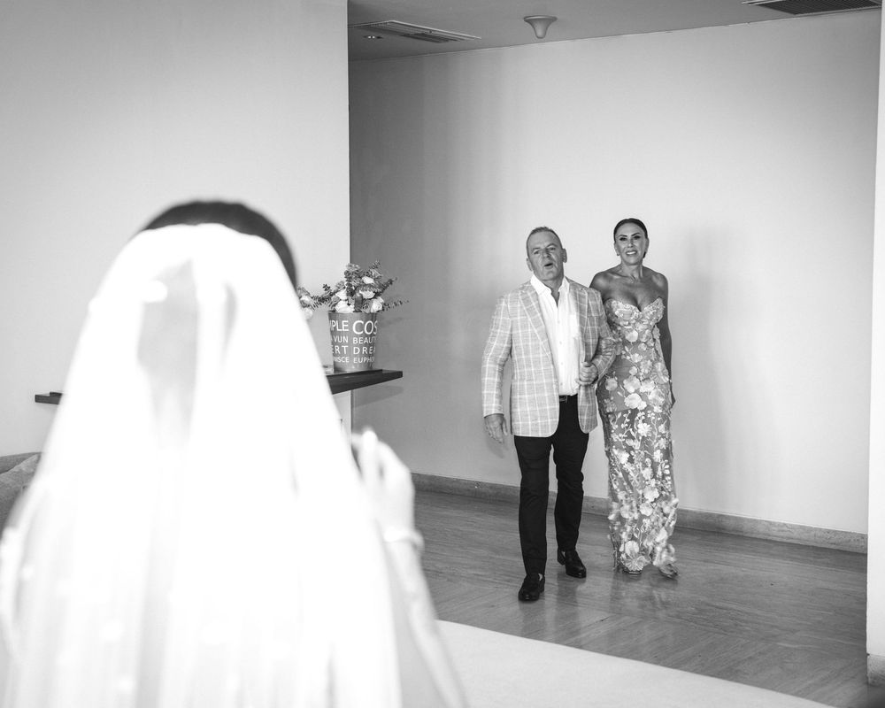 People walking through a minimalist white art gallery space with stark white walls and high ceilings.
