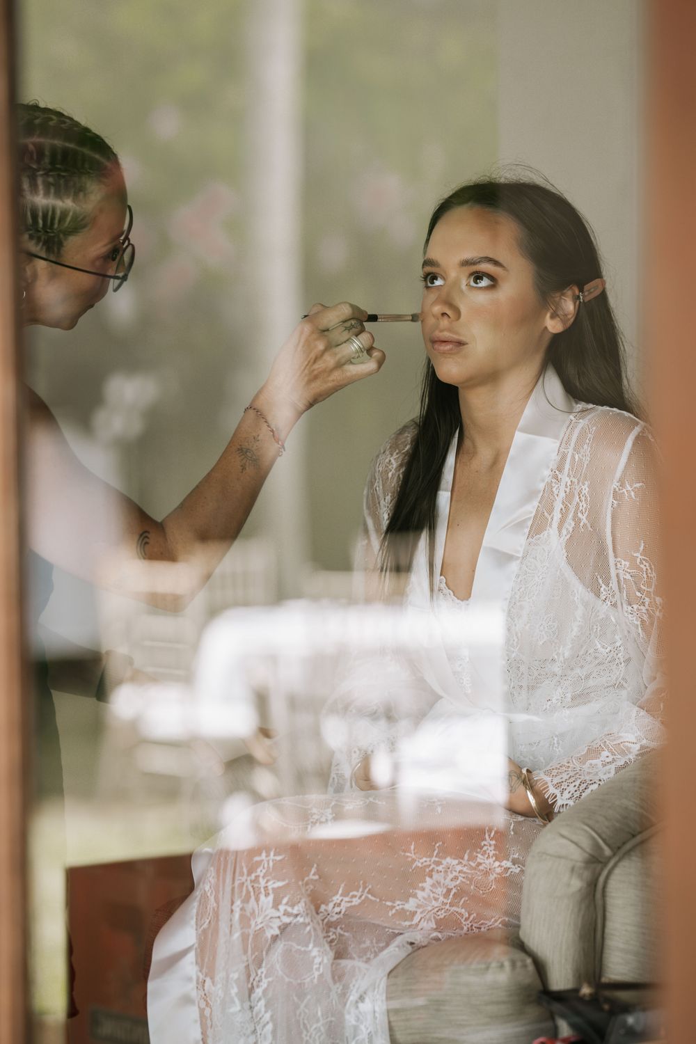 A series of reflective window frames show a bride in white lace getting ready for her wedding ceremony.