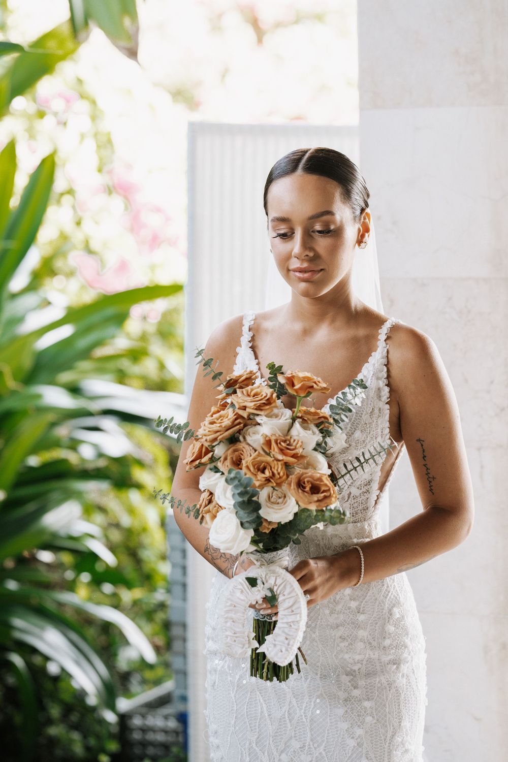 Elegant wedding bouquet with golden flowers and white accents held in a romantic natural light setting.