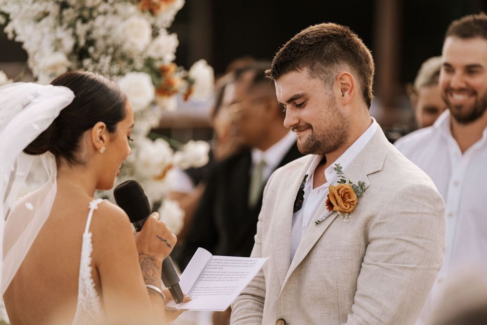 Wedding party in light colored attire smiling and celebrating outdoors during a summer ceremony.