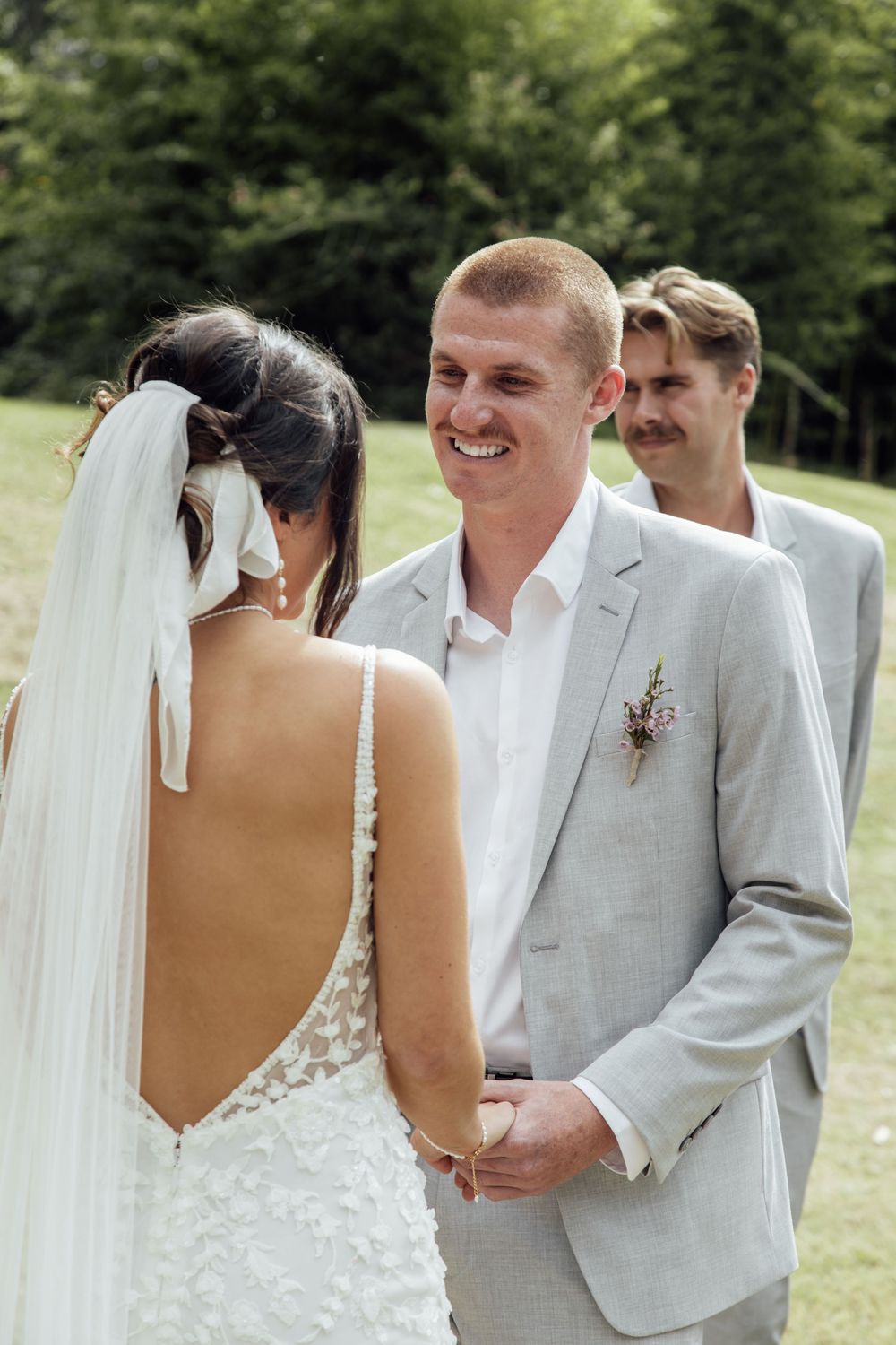 A bride and groom share a joyful moment during their outdoor wedding ceremony while exchanging vows.
