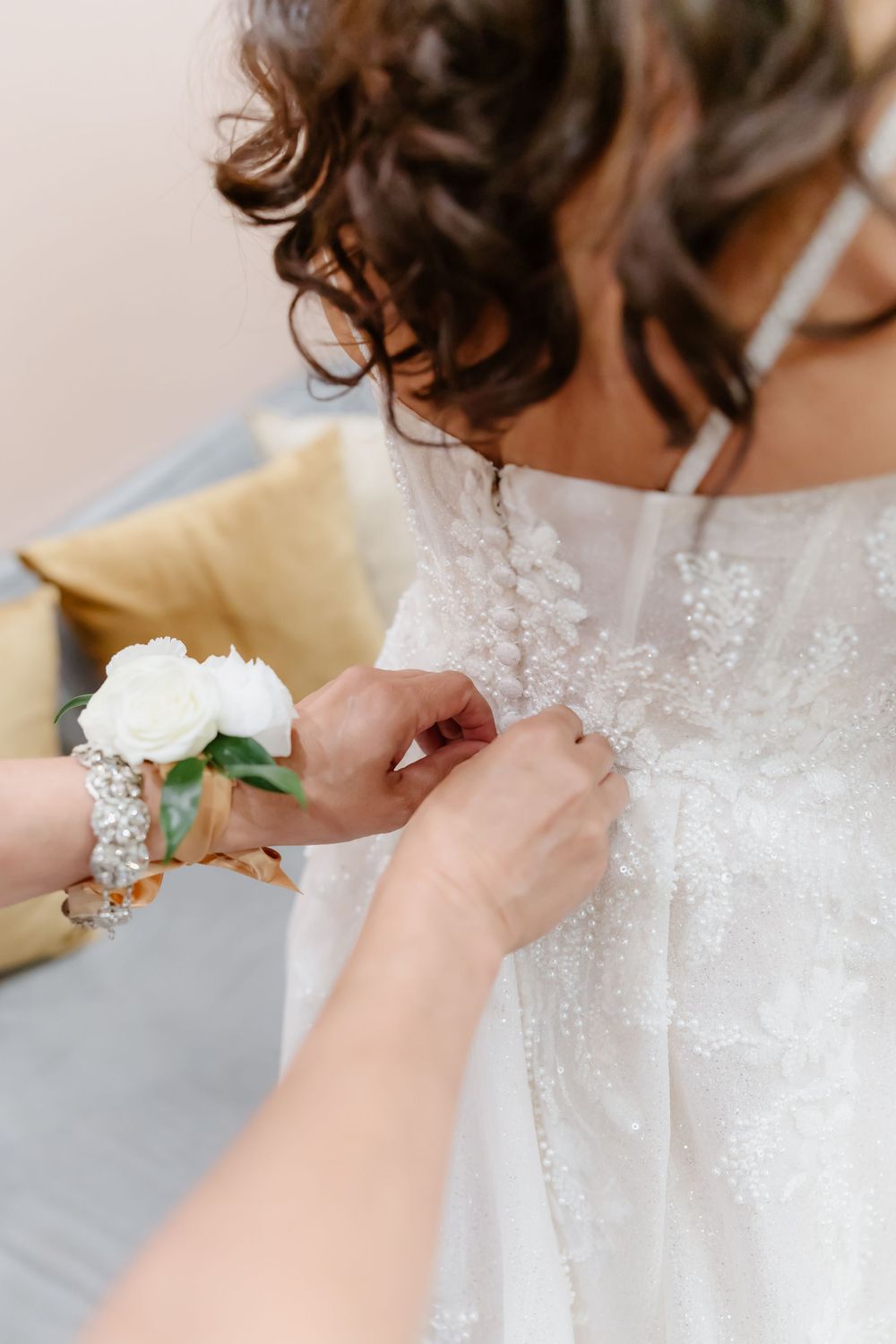 Close-up details of a delicate white lace wedding dress being adjusted.