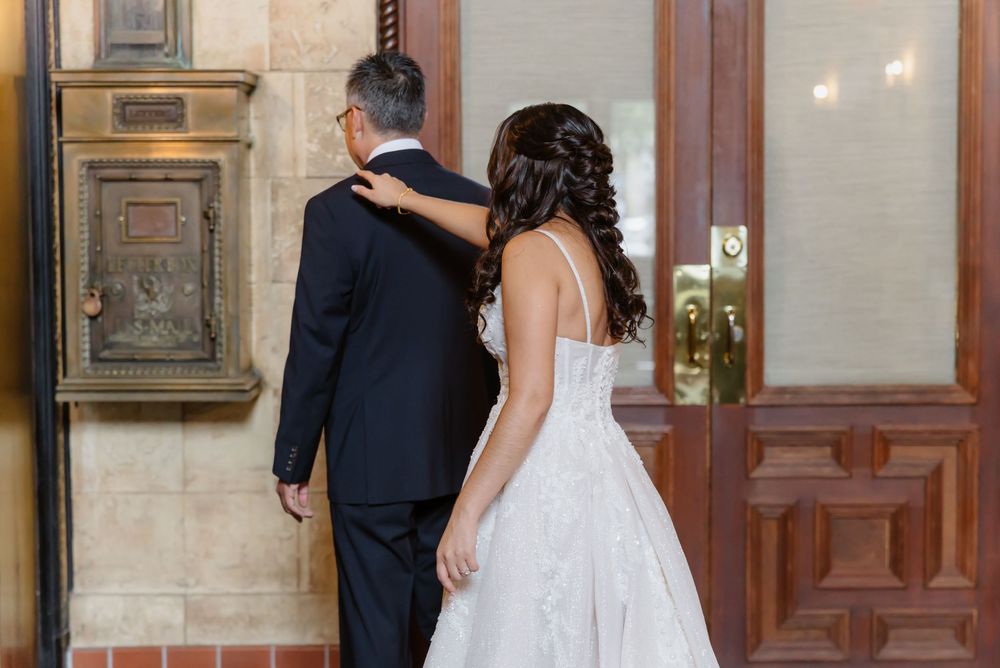 Traditional wedding couple stands outside a historic church entrance with rustic wooden doors and stone walls.