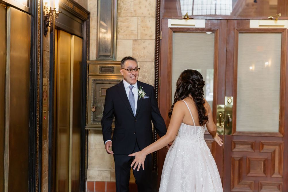Bride in a white wedding gown walks through wooden church doors during a religious ceremony.