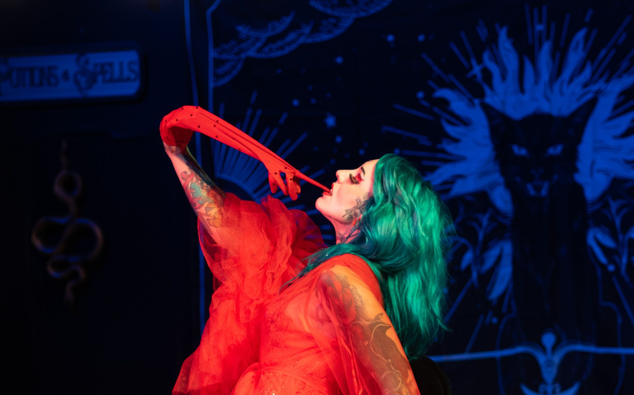 Dramatic pose with red fabric against mystical blue backdrop during stage performance. Quad Cities Event Photography