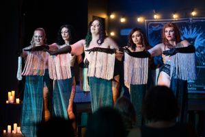 Group performance featuring coordinated outfits with fringed details on dimly lit stage. Quad Cities Event Photography