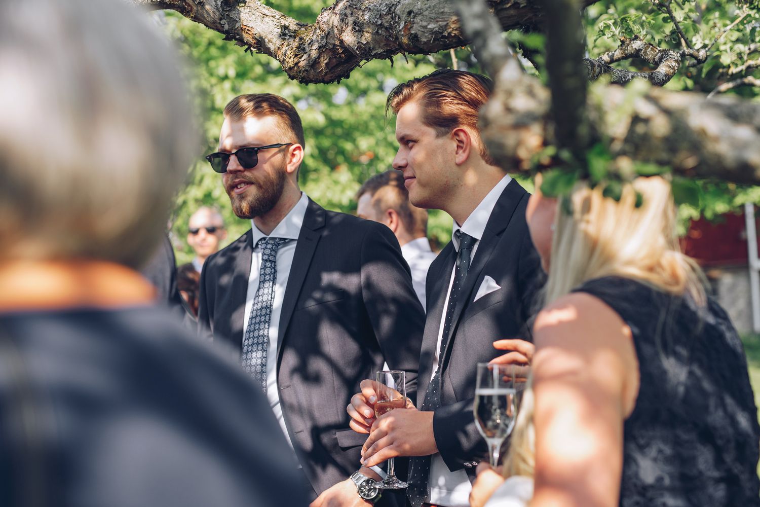 Bröllopsgäster som tar skydd under ett träd på minglet