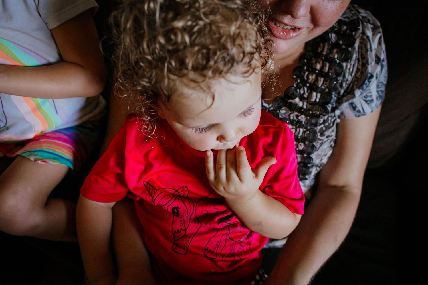 A sequence of photos showing a child in a red shirt with their hand touching their face.