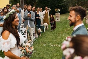 Wedding guests gather outdoors for a celebratory moment tossing confetti in the sunlight.