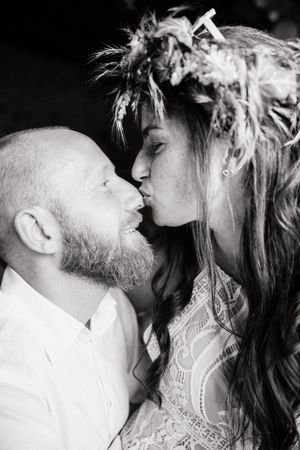 Black and white photo of a couple sharing a romantic kiss, bride wearing a floral crown and lace dress.