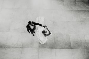 Aerial black and white photo of bride and groom sharing their first dance on a tiled floor at a wedding reception.