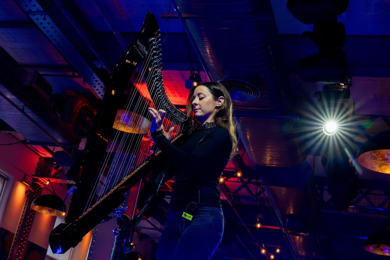 Color-saturated nightclub scene showing a drum kit illuminated by dramatic stage lighting and atmospheric effects.