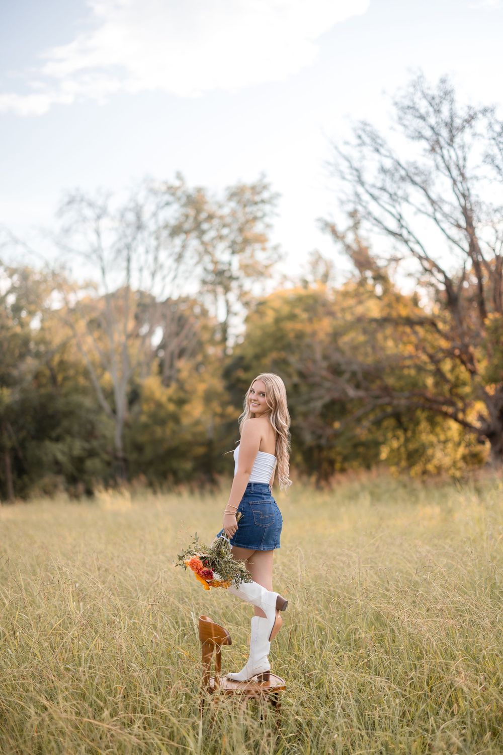 A casual summer scene with someone sitting on a rustic wooden stool in a golden field.
