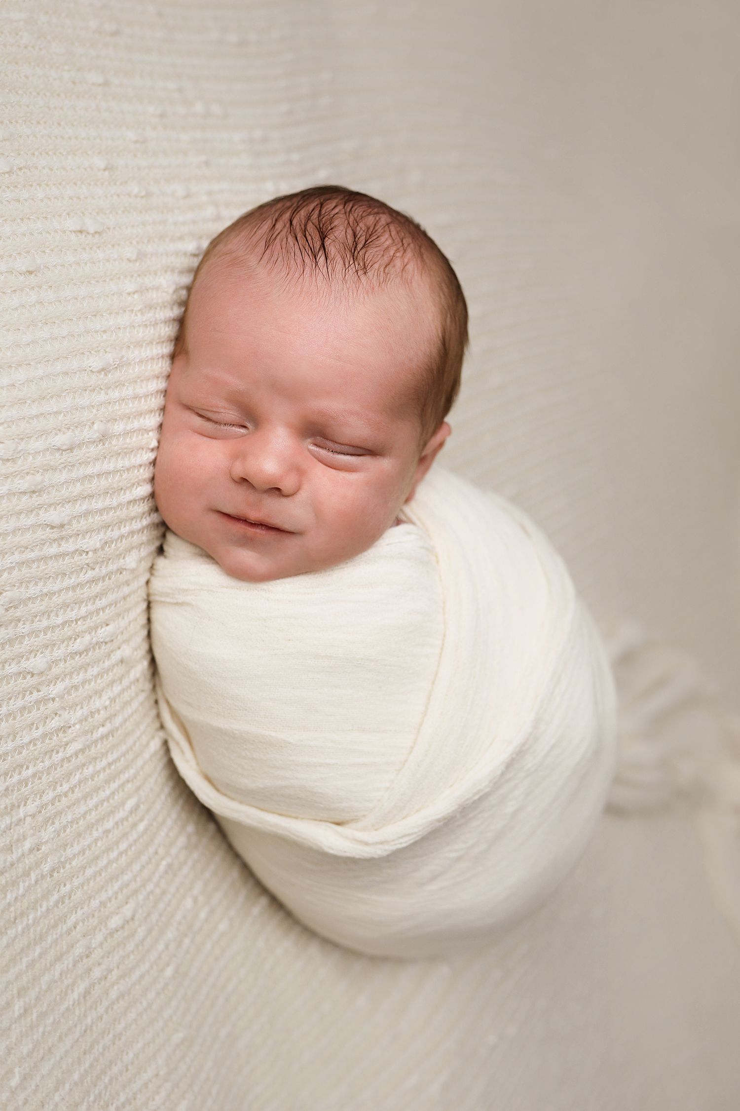 A series of five connected newborn portraits showing peaceful sleep wrapped in soft white fabric against a neutral background.