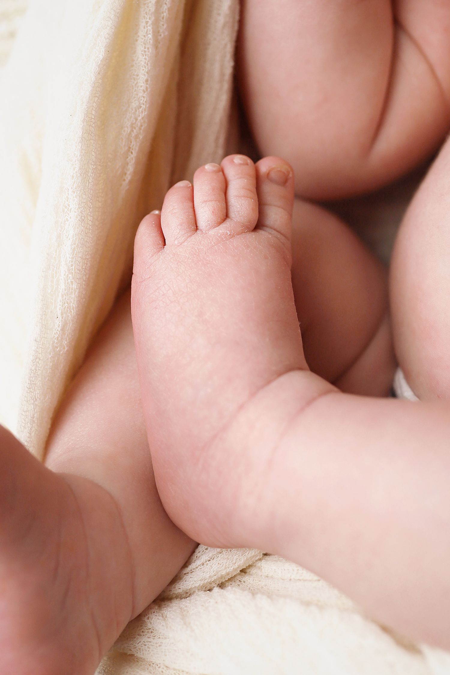 A series of connected macro photos showing pink baby fingers and hands against a light neutral background.