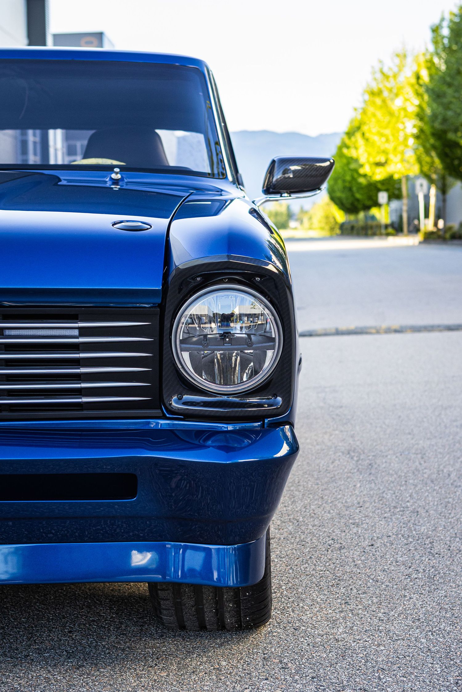 Close-up shots of a classic blue car showing headlights and front end details against a blurred asphalt background.
