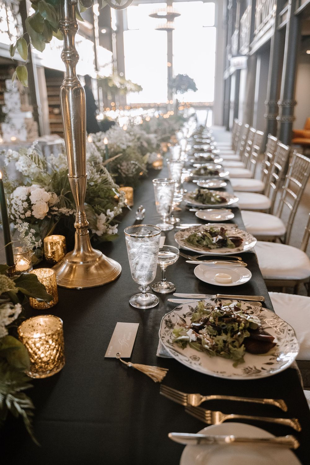 Wedding table settings with black linens, gold accents, and white floral centerpieces create an elegant atmosphere.