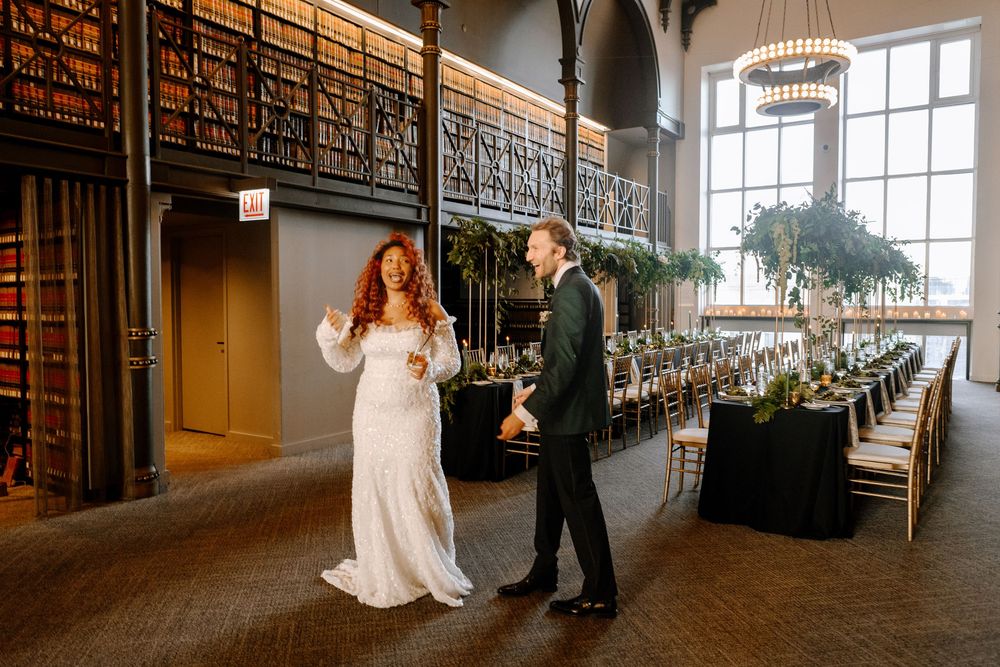 A romantic first look moment between wedding couple in an elegant venue with dramatic natural lighting and tall windows.