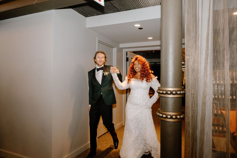 Wedding couple enjoying tender moments together in an elegant indoor venue with sheer curtains and warm lighting.