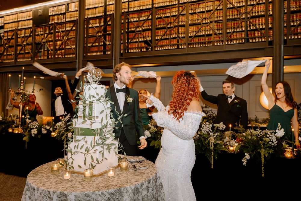 Guests dance and celebrate during a wedding reception in an elegant wood-paneled library venue.
