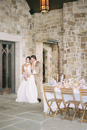 Stone chapel corridor with light wooden chairs arranged in rows and decorated with delicate floral arrangements for a wedding.