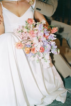 Delicate pink and purple flowers adorning a white wedding dress against a neutral background.