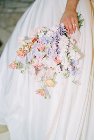 Close-up views of a delicate wedding bouquet with soft pink and lavender flowers against a white gown.
