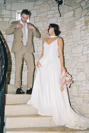 Wedding celebration in a rustic stone venue with flowing white gowns and formal attire.