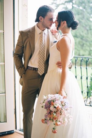 An intimate wedding moment captured by a window with soft natural lighting.