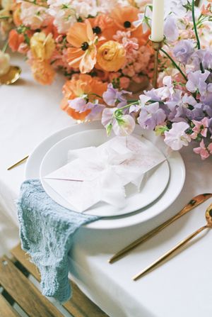 Elegant place settings with white plates and pastel coral and purple flowers on a crisp tablecloth.
