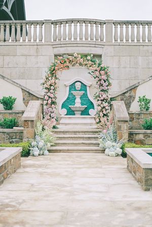 Elegant stone stairs with white railings decorated with pink floral arrangements and turquoise accents.