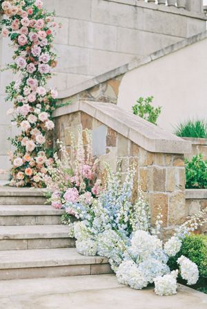 Stone staircase decorated with lush pink roses, hydrangeas and delicate floral arrangements for a wedding ceremony.