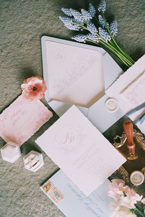 Wedding stationery in soft pink and white with delicate blue flowers and wax seals.