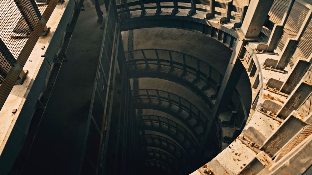 Aerial view of a circular parking garage structure with winding ramps and concrete architecture.