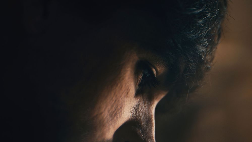 Dark silhouettes of multiple faces looking away in dramatic lighting against a blurred background.