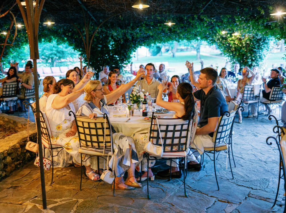 People gathered at tables for an outdoor evening dining event under string lights and trees.