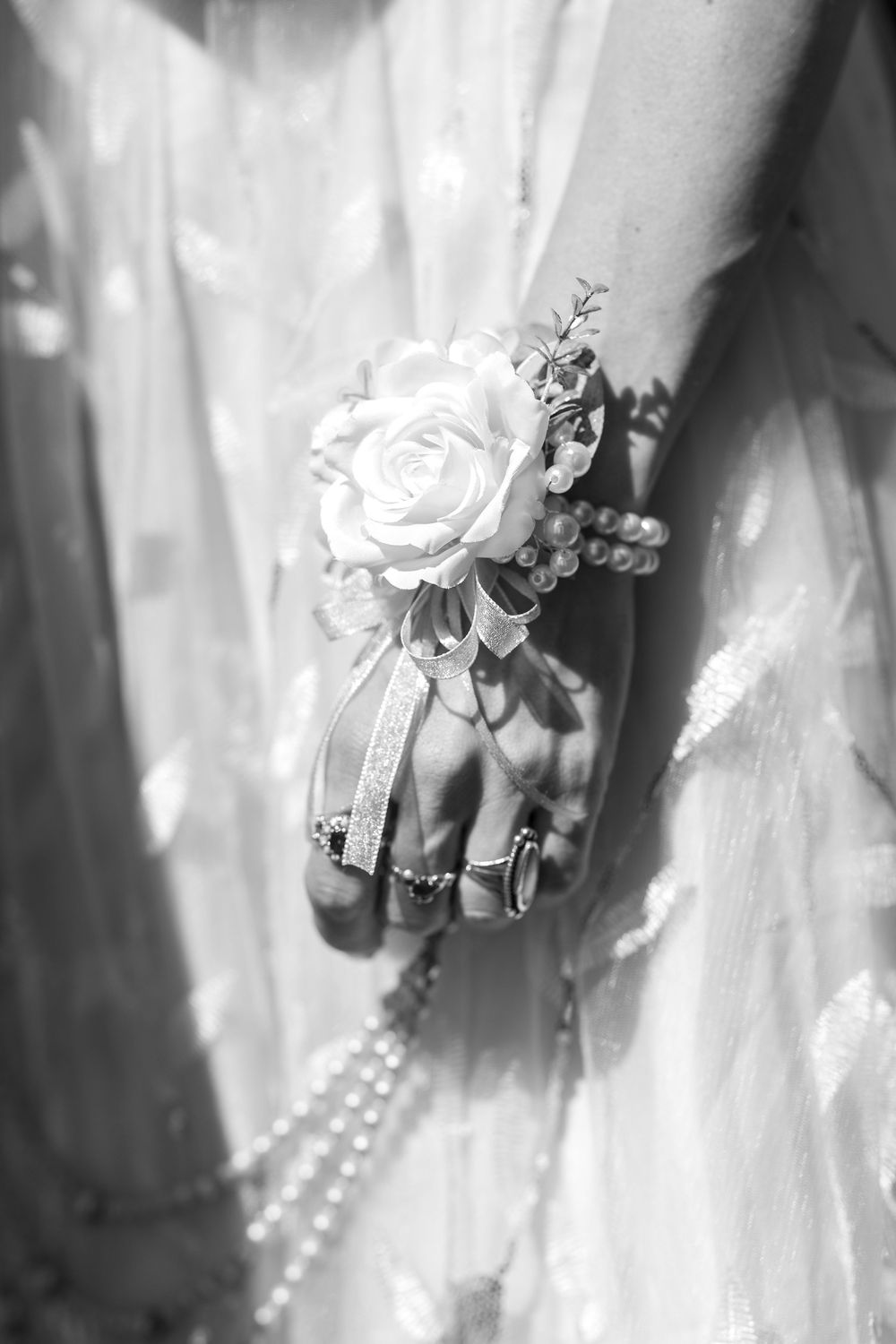 A set of black and white wedding photos showing pearl bracelets and delicate white rose corsages on wrists.