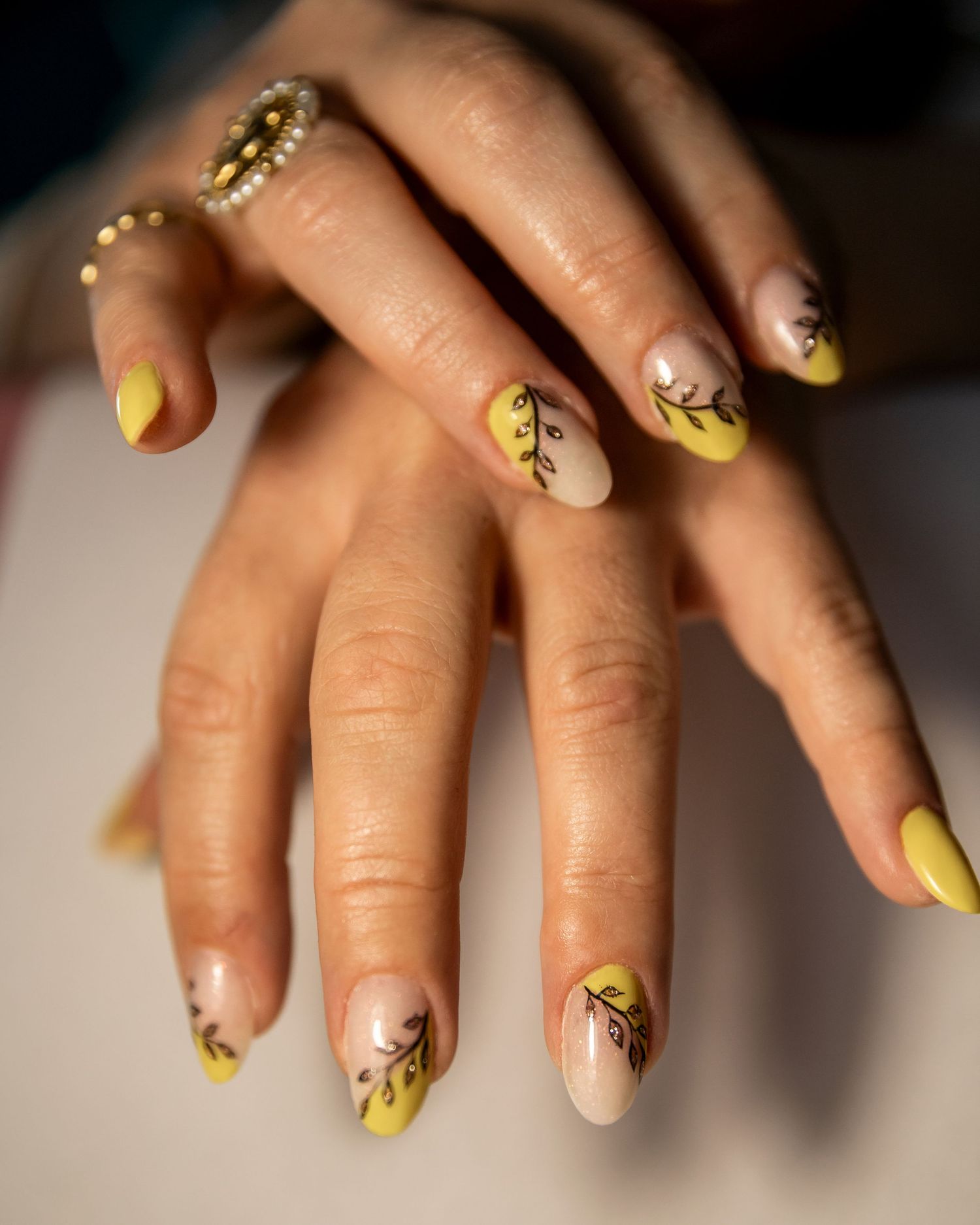 Yellow and black floral nail art design showcases intricate patterns on manicured fingernails.
