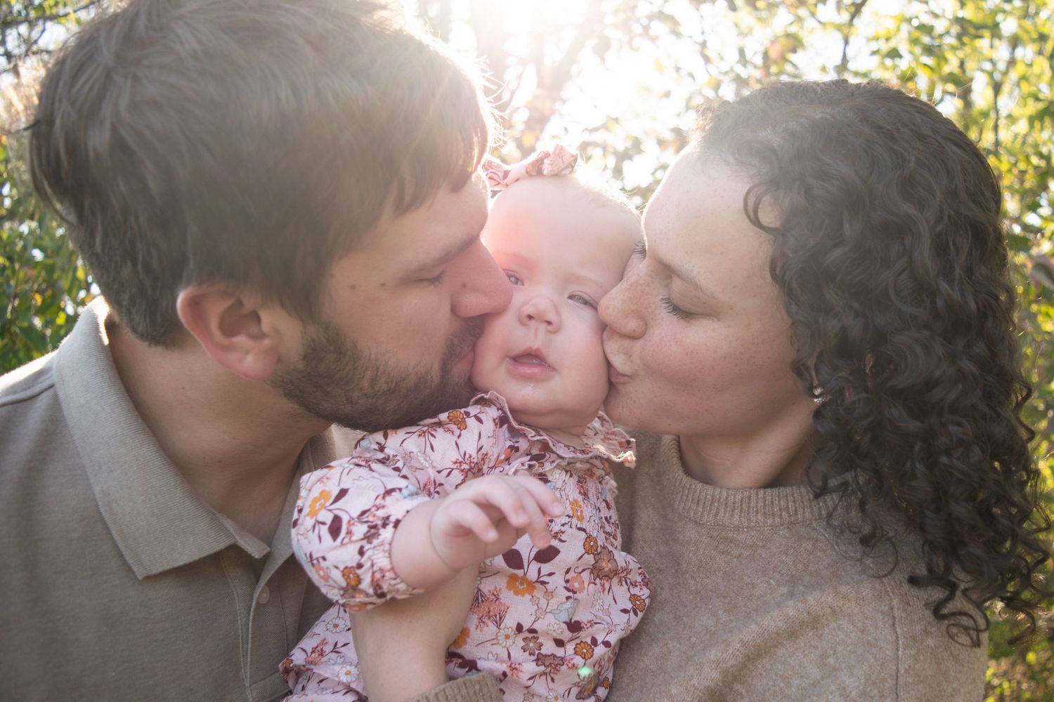 A mom and dad giving their daughter a kiss on both of her cheeks