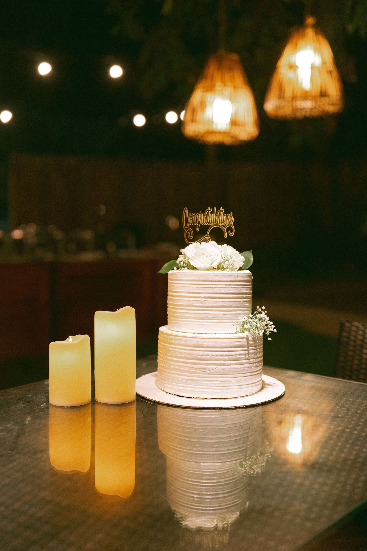 Elegant white wedding cake on table with glowing candles and ambient lighting by best wedding photographer in London & Birmingham