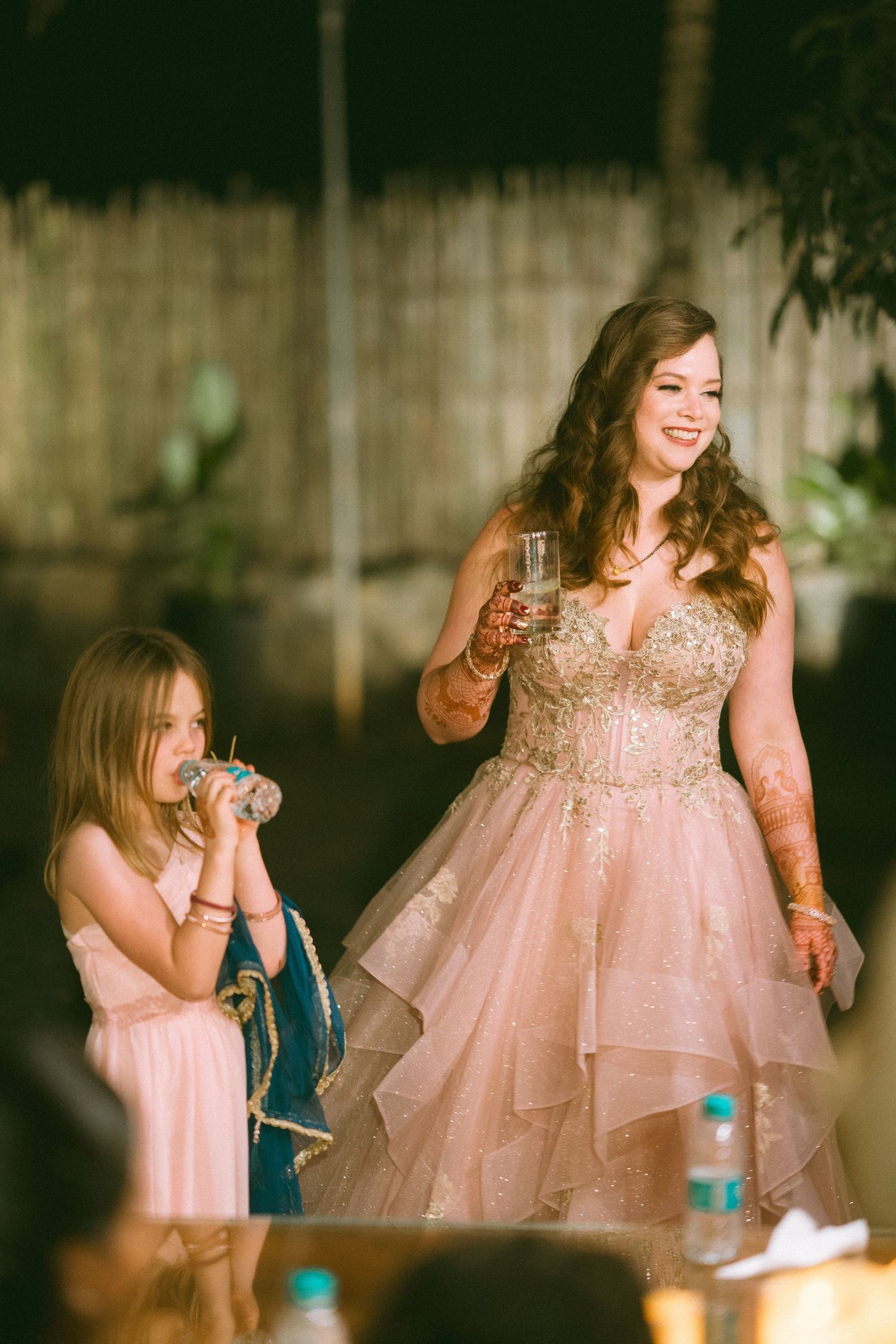 Guest in a pink ballgown celebrating joyfully at an outdoor evening wedding by the best wedding photographer in London & Birmingham