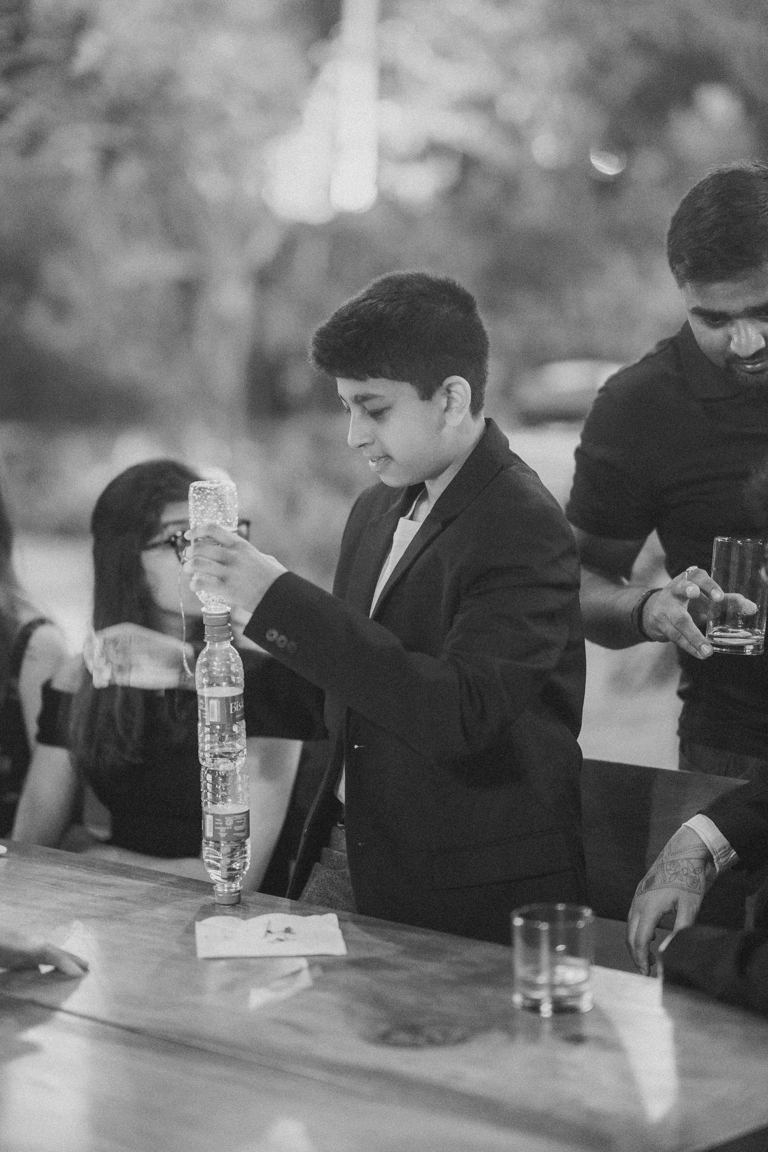 Guest in a black blazer pouring a drink at a wedding bar counter by a wedding photographer in London & Birmingham.