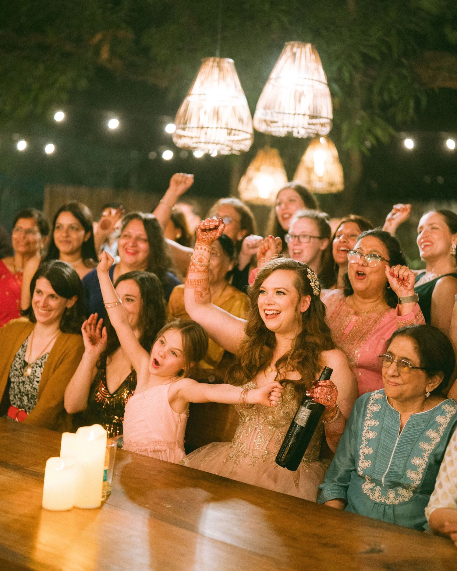 Wedding guests laughing and celebrating together at tables under warm lighting by the best wedding photographer in London & Birmingham