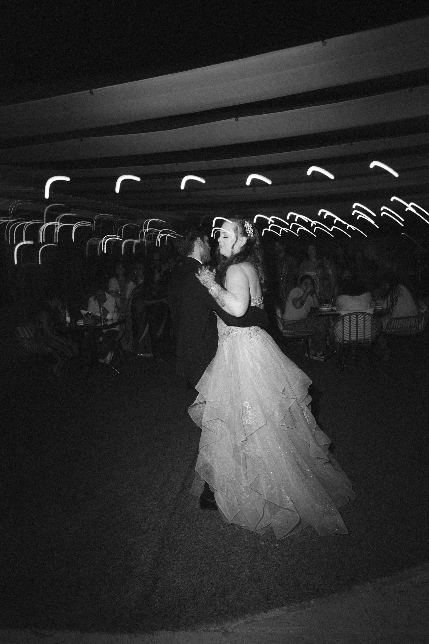 Bride in a flowing white wedding gown dancing in a dark reception hall by a wedding photographer in London & Birmingham.
