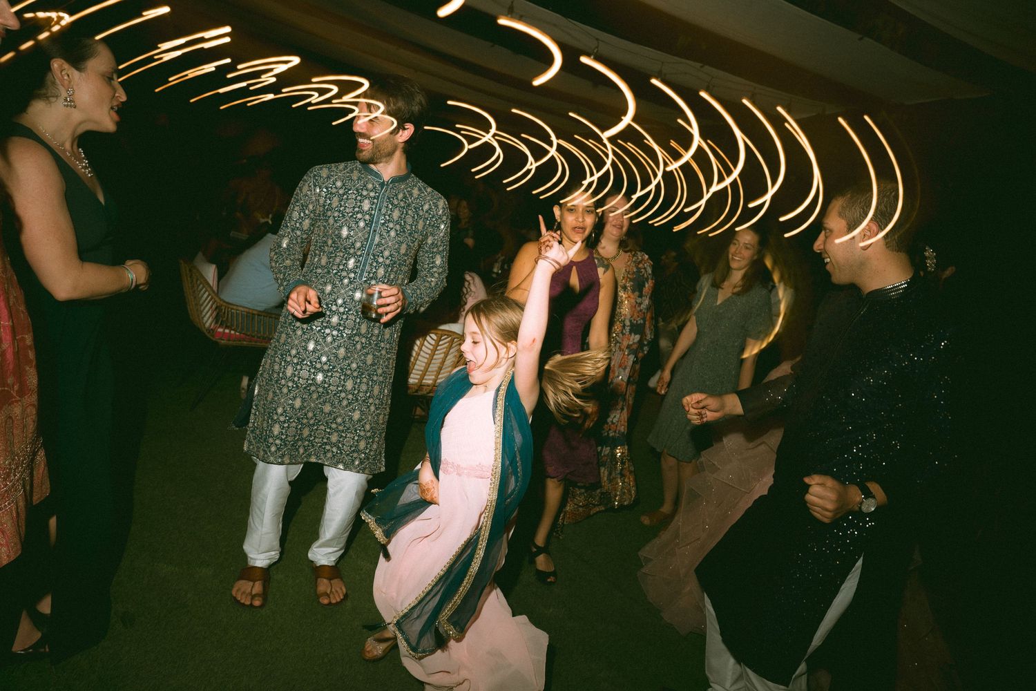 Wedding guests dancing and celebrating on dark dance floor with light trails overhead by a wedding photographer in London Birmingham