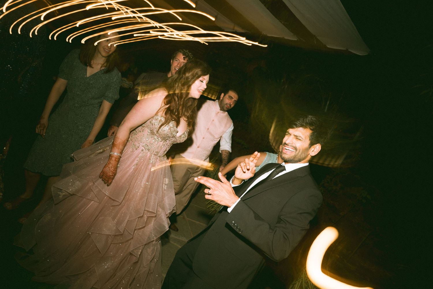 Couple dancing energetically at their wedding reception under decorative lighting by a wedding photographer in London & Birmingham
