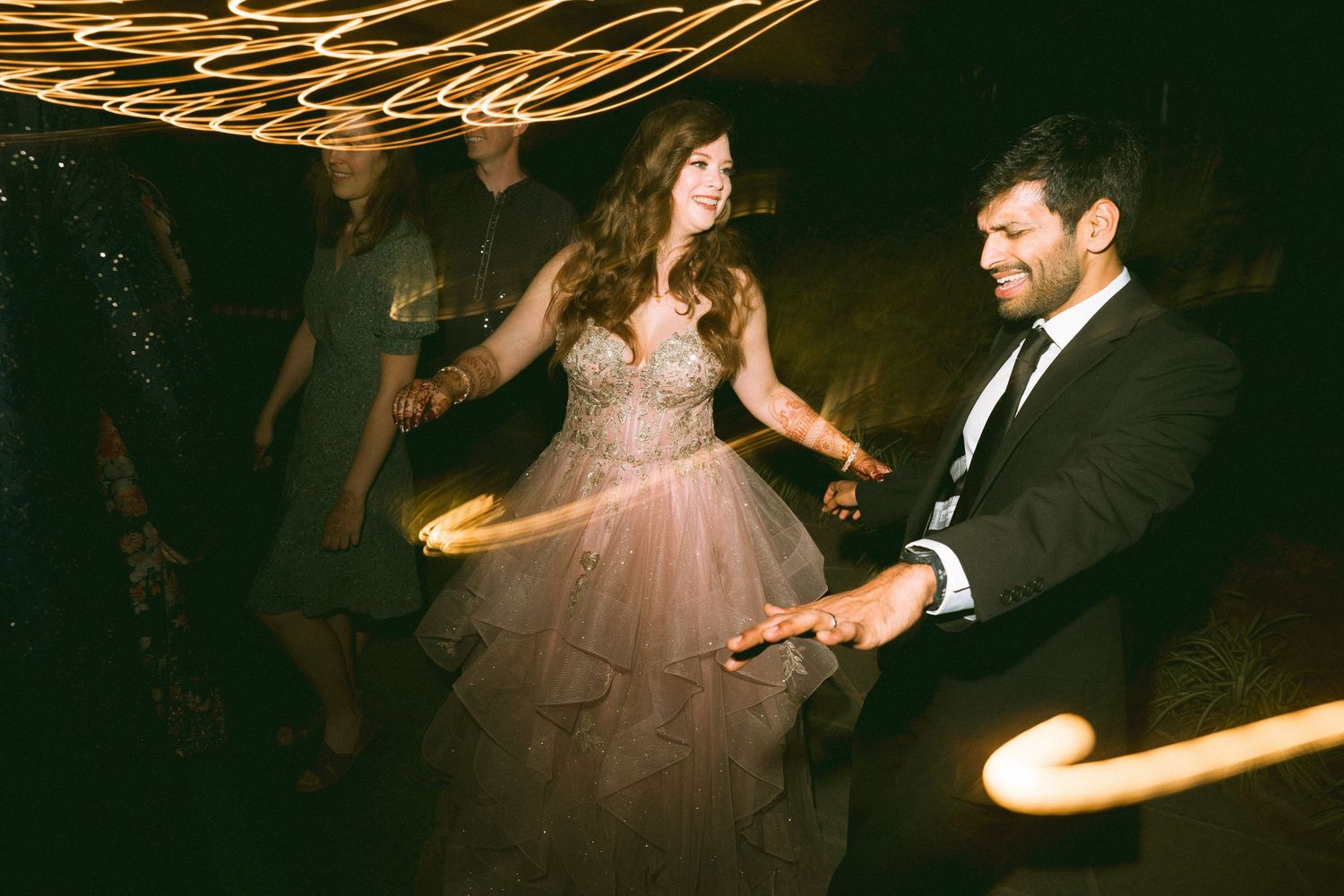 Couple dancing energetically at their wedding reception under decorative lighting by a wedding photographer in London & Birmingham