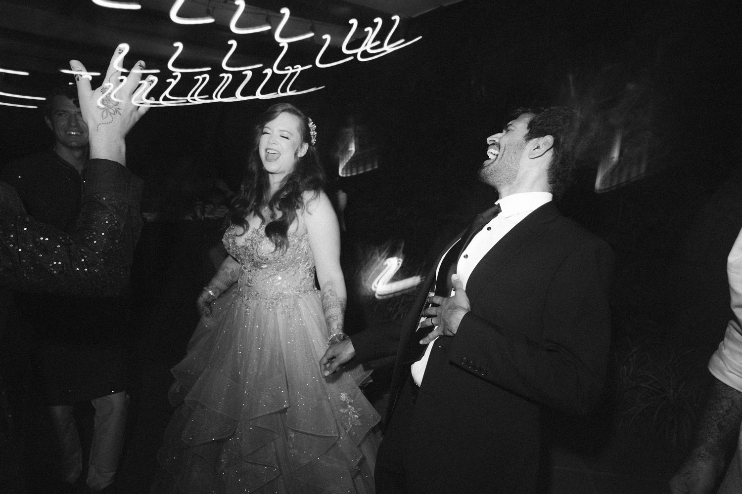 Couple dancing joyfully under streaked lighting at their wedding reception by a wedding photographer in London & Birmingham.